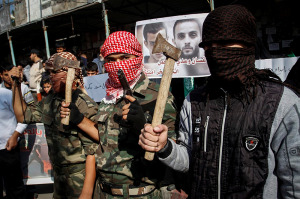 Terroristas de Hamas en Gaza tienen ejes y una pistola en la celebración de una masacre en una sinagoga de Jerusalén el 18 de noviembre de 2014. (Foto: cama Rahim Khatib / Flash90)