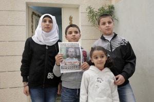 Family members of Ibrahim Akkari hold his picture as a martyr after he was shot following his driving his car into a group of people at a Jerusalem light rail station.