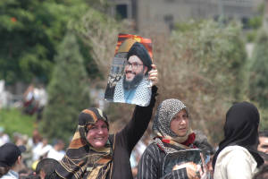 A Lebanese woman carries the portrait of Hezbollah leader Nassrallah. (Photo: Sadik Gulec/ shutterstock)