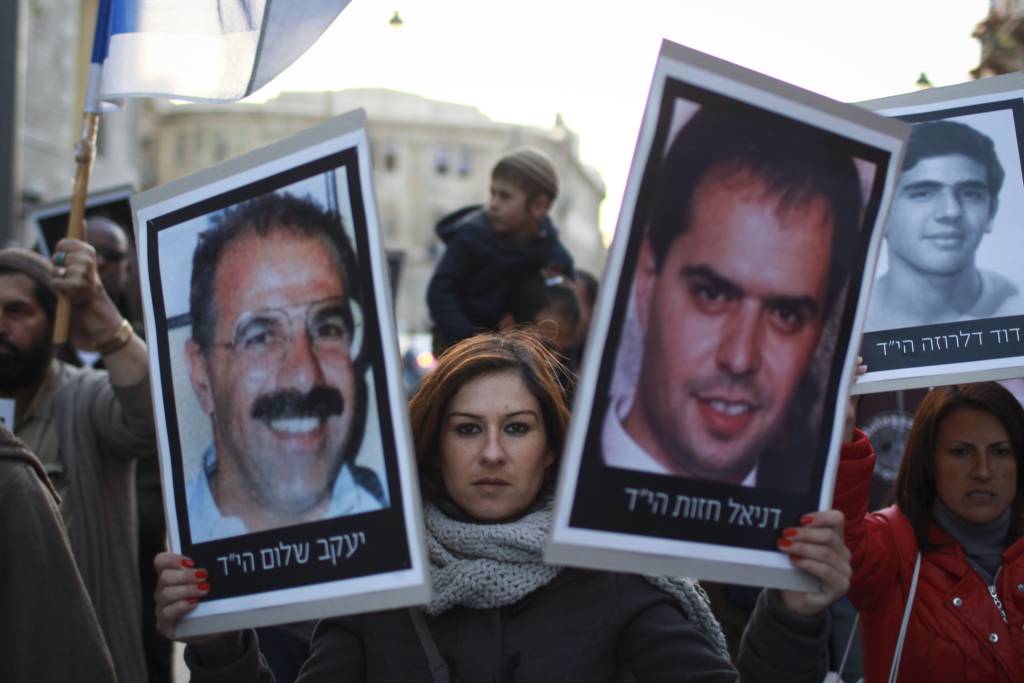 Demonstrators carry pictures of victims killed by Palestinian terrorists. (Hadas Parush/Flash90)