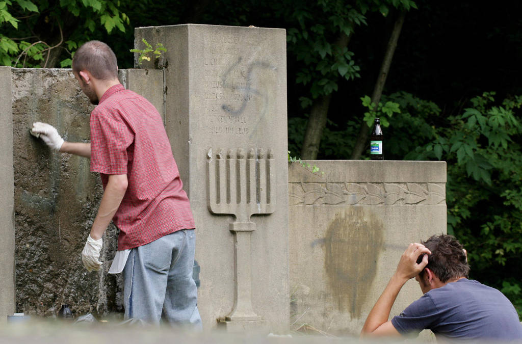 Polish and Jewish youths remove painted swastikas from desecrated gravestones