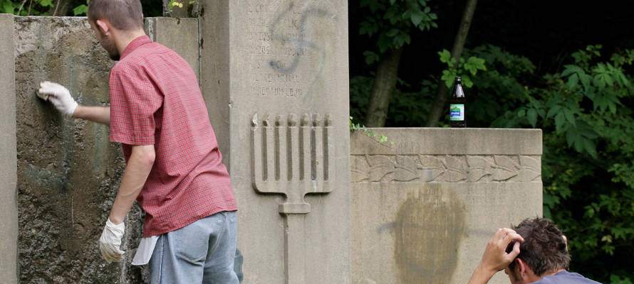 Polish and Jewish youths remove painted swastikas from desecrated gravestones