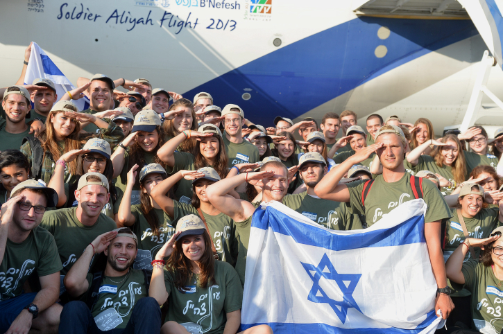 New immigrants from USA and Canada salute and hold up Israeli flags as they arrive in a special "Soldier Aliyah Flight