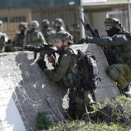 IDF soldiers take positions during a raid to arrest a Palestinian