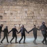 Men dance in the snow at the Western Wal, in Jerusalem. (Noam Rivkin Fenton/Flash90)