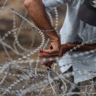Palestinian tires to breach barbed wire fence installed along the border. (Wissam Nassar/Flash90)