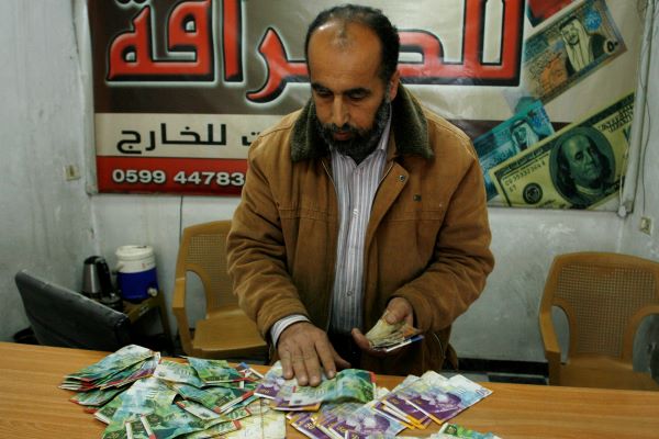 Palestinian man displays Israeli shekels. (Abed Rahim Khatib/Flash90)