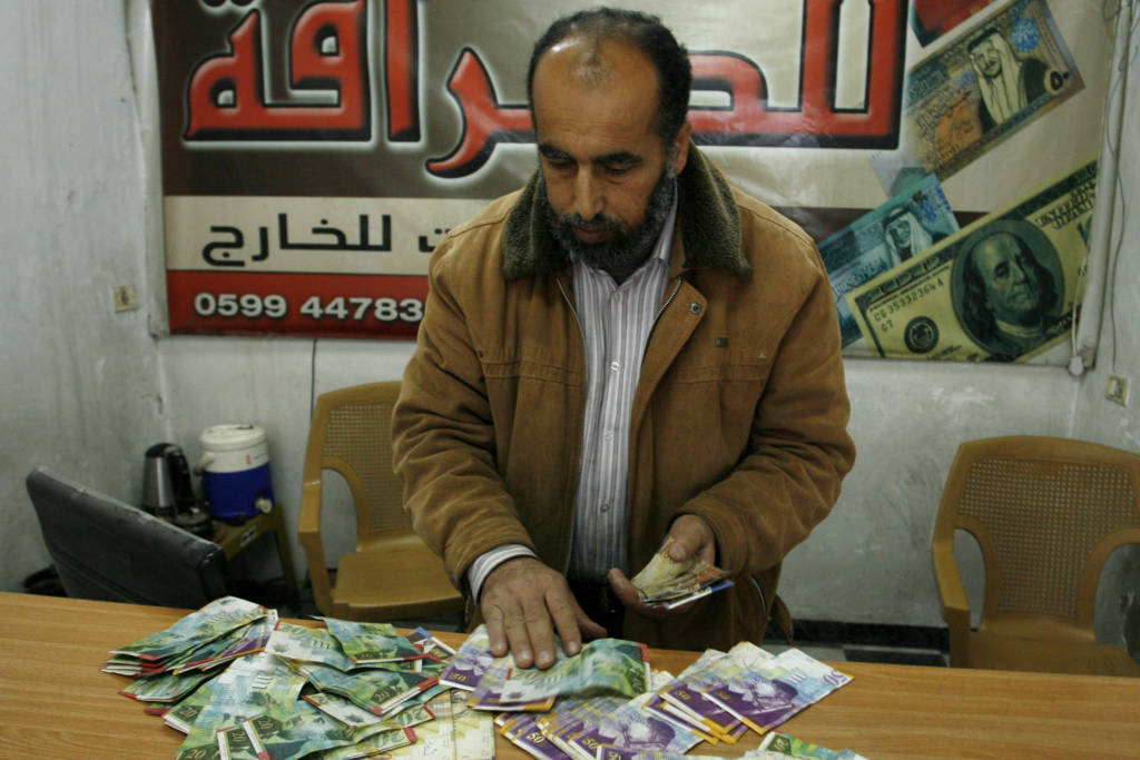 Palestinian man displays Israeli shekels. (Abed Rahim Khatib/Flash90)