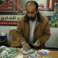 Palestinian man displays Israeli shekels. (Abed Rahim Khatib/Flash90)