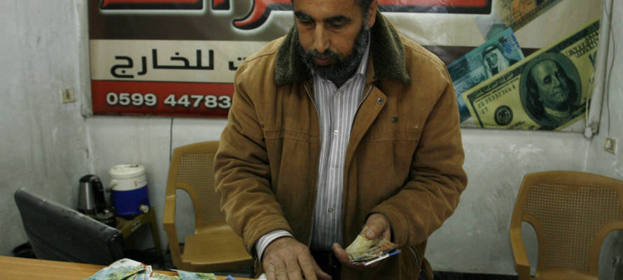 Palestinian man displays Israeli shekels. (Abed Rahim Khatib/Flash90)