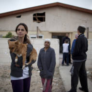 Israelis next to a house damaged by Palestinian rocket during a previous attack. (AP Photo/Oded Balilty)