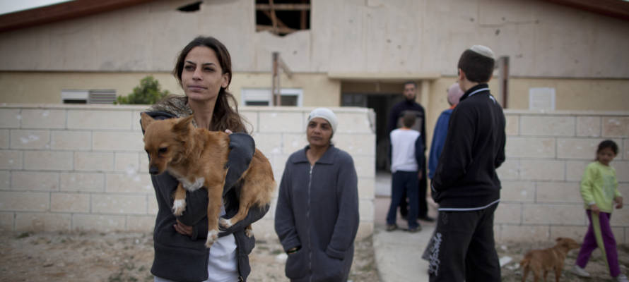 Israelis next to a house damaged by Palestinian rocket during a previous attack. (AP Photo/Oded Balilty)