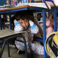 At a school in Ashkelon, children hide under chairs and tables while practicing what to do during an eventual Qassam Rocket attack. (Edi Israel/Flash90)