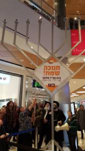 Ginny Nissenbaum lights the Chabad menorah at Malcha Mall (Tsivya Fox-Dobuler)