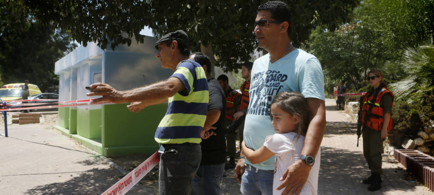 Israelis near the remains of a rocket fired by Palestinian terrorists
