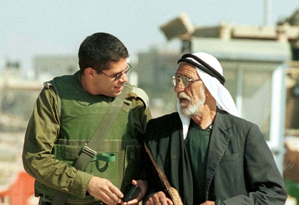 An Israeli soldier walks with a senior