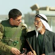 An Israeli soldier walks with a senior