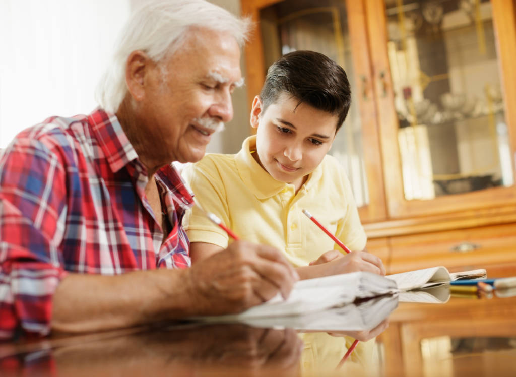 elderly man helps boy with homework