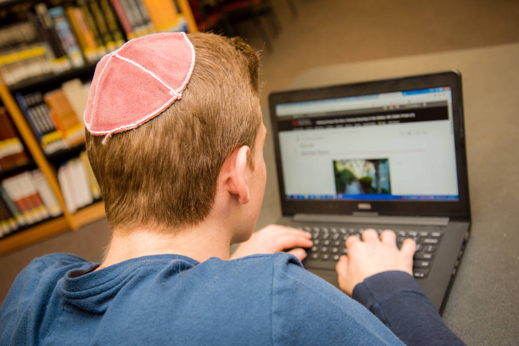 student with kippa on computer