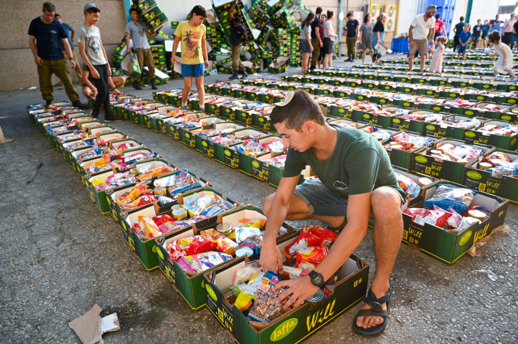 .Israeli soldiers and volunteers pack food for families in need
