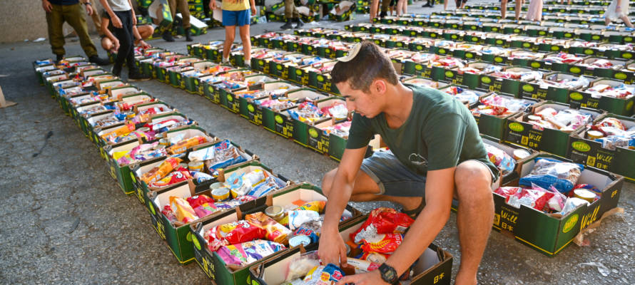 .Israeli soldiers and volunteers pack food for families in need