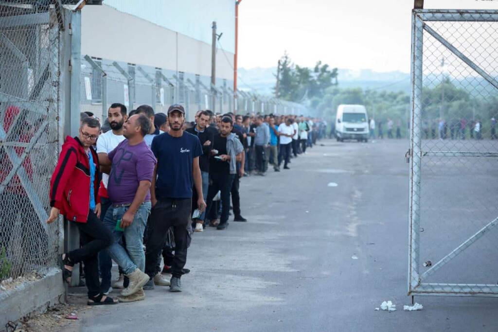 Workers from Gaza stand in line to enter Israel